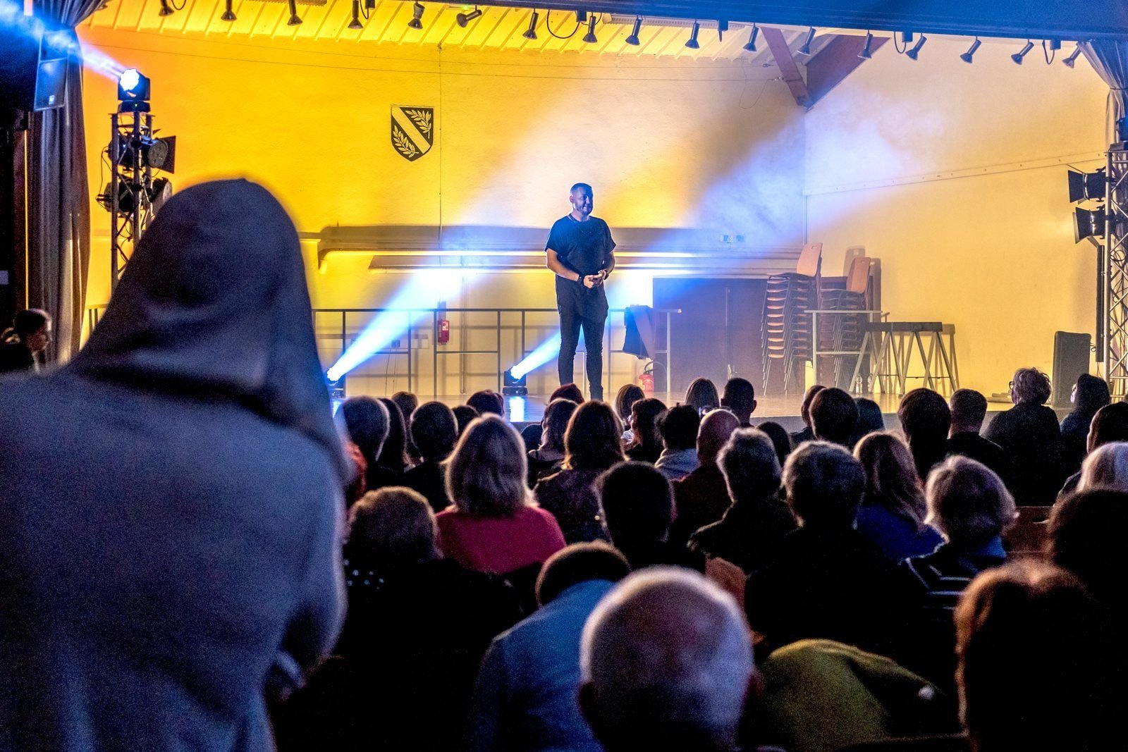 Le spectacle d'hypnose vu depuis la salle : R'Key seul sur scène sous les projecteurs, devant le public