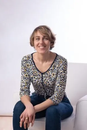 Portrait de Roselyne Wagner, hypnothérapeute à Erstein, souriante, assise dans un fauteuil blanc
